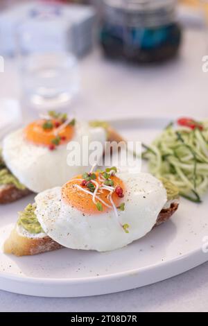 Tasty and beautiful fried benedict eggs served on avocado toast breakfast close up Stock Photo