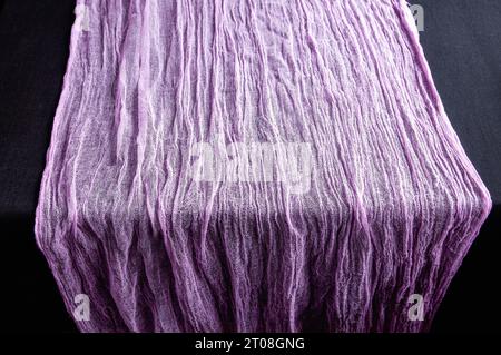 Lilac gauze scarf on a black background. Close-up. Stock Photo