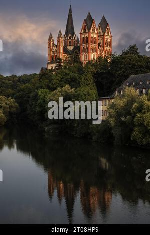 Late Romanesque / Early Gothic Cathedral of Saint George in Limburg an der Lahn, Hesse, Germany, reflected in the River Lahn.  The cathedral was built late 1100s / early 1200s.  It has seven towers of varying heights, including one with a slightly curving spire, and used to feature on pre-Euro Deutsche Mark banknotes.  It owes its exuberant and colourful exterior to painstaking restoration work in the 1960s and ‘70s, with colours determined by traces of original paint. Stock Photo