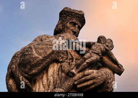 Statue of St John of Nepomuk (c. 1345 - 1393), patron saint of bridges, cradling the crucified Christ.  On the Alte Lahnbrücke (Old Lahn Bridge) in Limburg an der Lahn, Hesse, Germany. The statue was created in 1966 by the German sculptor Karl Matthäus Winter (1932 - 2012).  An original statue of 1714 is in the local archive. Stock Photo