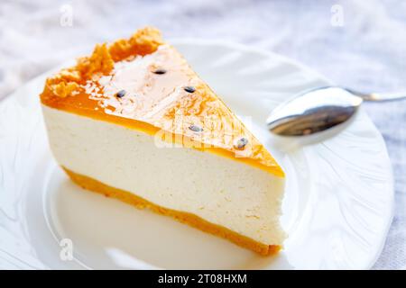 Delicious fresh baked multi-layered mango passionfruit cheesecake slice with fruit jelly glaze on white plate close up. Stock Photo