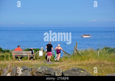 Elderly couple going down to the beach for a swim in Cushendun, County Antrim, Northern Ireland Stock Photo