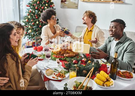 big cheerful and multiracial family having great time celebrating Christmas and exchanging gifts Stock Photo