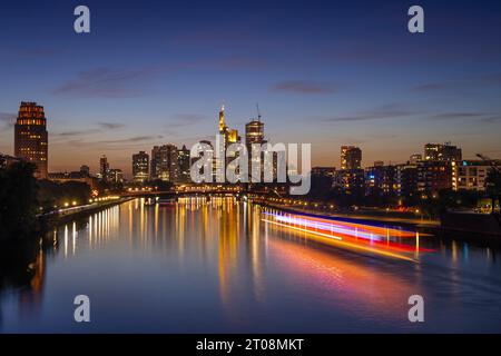 A ship sails on the Main towards Frankfurt's glowing bank skyline in the evening. (long exposure), Osthafen, Frankfurt am Main, Hesse, Germany Stock Photo