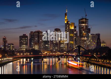 A ship sails on the Main towards Frankfurt's glowing bank skyline in the evening. (long exposure), Osthafen, Frankfurt am Main, Hesse, Germany Stock Photo