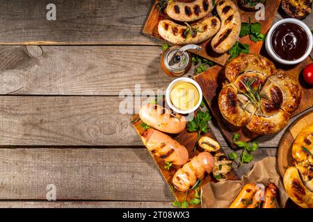 Mix bar-b-q sausages - bavarian, round, gumberland, bratwurst with ketchup, mustard barbeque sauce. Various bbq grilled sausages flat lay on wood back Stock Photo