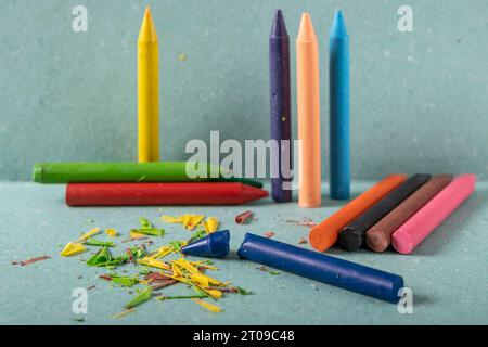 A series of brightly colored wax crayons are arranged on a green stand and background Stock Photo