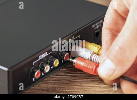 Close-up hand connecting a plug to a color music amplifier. Stock Photo