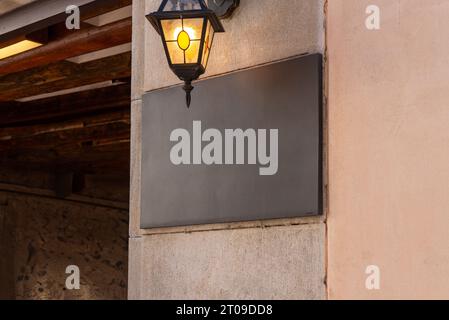 Square restaurant sign, placed on a wall under a street lamp, provides an ideal space for logo mockup promotion Stock Photo