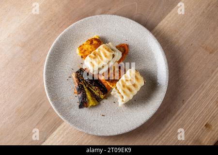 From above of tasty white fish fillets grilled with pepper and eggplant served on plate Stock Photo