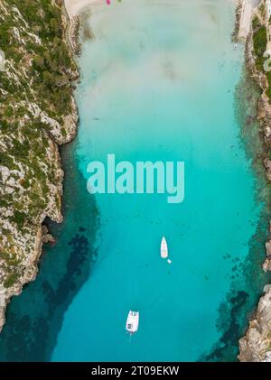 Aerial top view of transparent turquoise water of sea on Menorca island with floating sailboat on surface Stock Photo