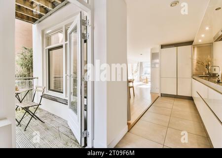 Passageway with open door by open plan illuminated kitchen in new contemporary home Stock Photo