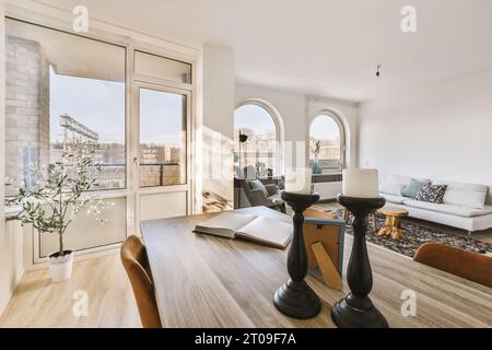 Candlestick holder with open book on dining table in front of furniture in living room of modern apartment Stock Photo