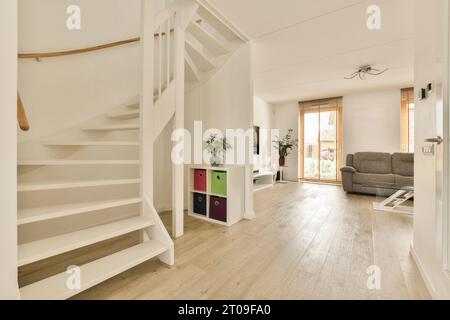 White spiral staircase at passageway by living room with couch in contemporary home Stock Photo