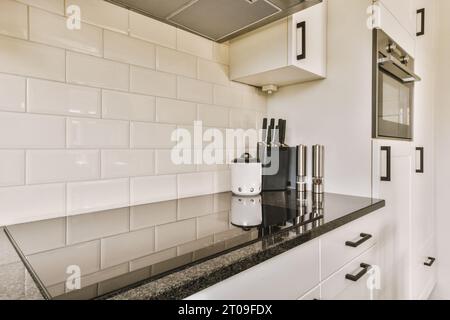 Interior of kitchen with black countertop and white backsplash tiles in modern apartment Stock Photo