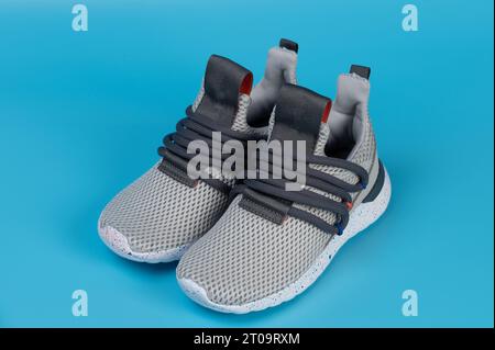 Grey laceless pair kid sport shoes perspective view isolated on blue studio background Stock Photo