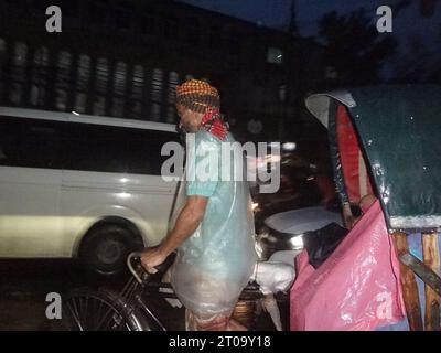 Dhaka, Bangladesh. 5th Oct, 2023. A rickshaw puller uses a plastic sheet to shield them from the rain. The capital's daily life was reportedly disrupted by a continuous rain depression. (Credit Image: © MD Mehedi Hasan/ZUMA Press Wire) EDITORIAL USAGE ONLY! Not for Commercial USAGE! Stock Photo