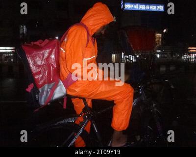 Dhaka, Bangladesh. 5th Oct, 2023. A delivery boy uses a raincoat during rain in Dhaka. The capital's daily life was reportedly disrupted by a continuous rain depression. (Credit Image: © MD Mehedi Hasan/ZUMA Press Wire) EDITORIAL USAGE ONLY! Not for Commercial USAGE! Stock Photo