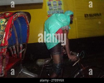 Dhaka, Bangladesh. 5th Oct, 2023. A rickshaw puller uses a plastic sheet to protect from rain in Dhaka. The capital's daily life was reportedly disrupted by a continuous rain depression. (Credit Image: © MD Mehedi Hasan/ZUMA Press Wire) EDITORIAL USAGE ONLY! Not for Commercial USAGE! Stock Photo