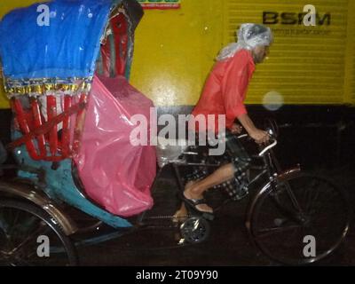 Dhaka, Bangladesh. 5th Oct, 2023. A rickshaw passenger uses a plastic sheet to protect from rain in Dhaka. The capital's daily life was reportedly disrupted by a continuous rain depression. (Credit Image: © MD Mehedi Hasan/ZUMA Press Wire) EDITORIAL USAGE ONLY! Not for Commercial USAGE! Stock Photo