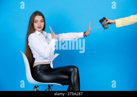 Serious, pretty girl making stop gesture for crop anonymous hand offering beverage in studio. Stock Photo