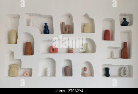Series of pottery display made of clay, in white stucco wall finishes and textured white paint ledges, open niche of ceramic pots, display. Stock Photo
