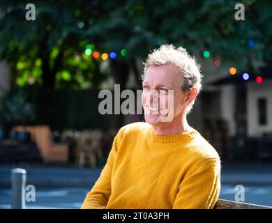 Portrait of a 55 yo white man, smiling and wearing a yellow sweater, Koekelberg, Brussels, Belgium Stock Photo