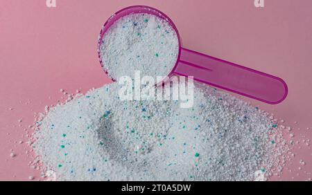 Washing powder in plastic spoon on pink background top view. High quality photo Stock Photo