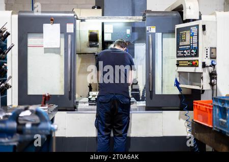 Man working on a steel pieces factory with a professional industrial machine Stock Photo