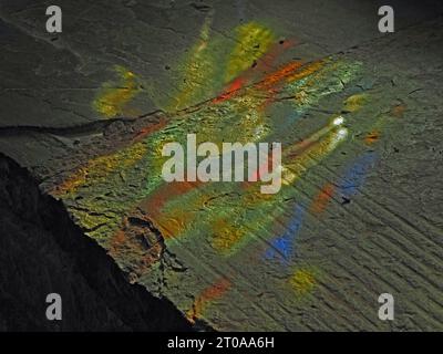 abstract splash of colour from sunlight projected through church stained glass window falling onto textured stone interior window ledge Stock Photo