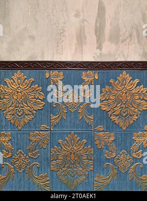 3D Vinyl Tiles, crafted in classical Baroque European and Morovian Pattern in teal blue and golden color engravings, with cement concrete wall Stock Photo