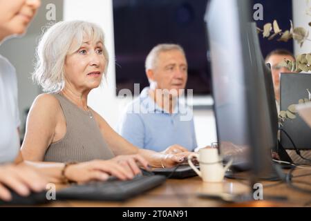 Old woman learning computer programs in training room Stock Photo
