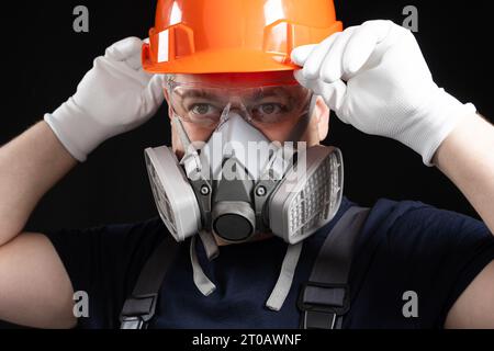 A man wearing a helmet, respirator and goggles on a black background Stock Photo