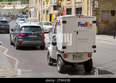 Valletta, Malta - 3 August 2023: Small motoized delivery vehicle operated by FedEx driving on a road in the island's capital Valletta Stock Photo