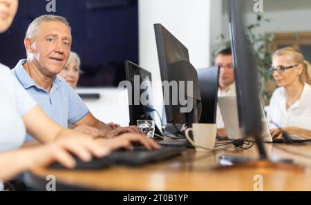 Old man learning computer programs in training room Stock Photo
