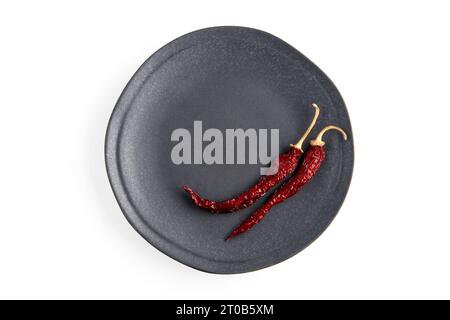 Two hot red capsicums on a gray ceramic plate isolated on a white background. Top view with copy space Stock Photo