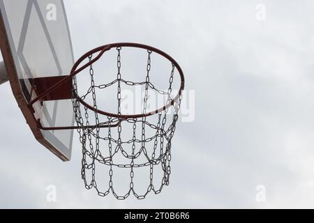 The basketball hoop on left side of photo is on an outdoor sports court against a light background. The concept of an active lifestyle Stock Photo