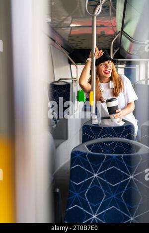 City lifestyle photography. Young joyful woman laughing while traveling city bus. Urban life and youth. Public transportation. Stock Photo