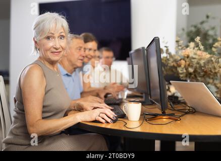 Old woman learning computer programs in training room Stock Photo