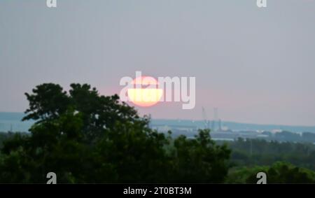 The setting sun is split in two by passing clouds as it descends over the harbor. Stock Photo