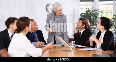 Experienced female businesswoman discussing project with colleagues Stock Photo
