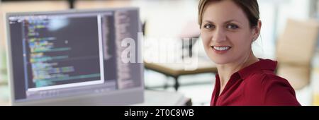 Smiling woman app developer writes code in company office Stock Photo