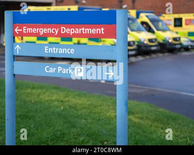 An Emergency Department sign with a row of ambulances in a row behind. Stock Photo