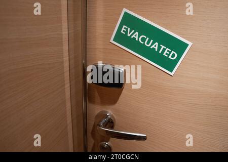 Schiffskabine mit einem Schild Evacuated Tuer einer Schiffskabine mit einem gruenen Schild und weissen Buchstaben auf dem das Wort Evacuated steht. Dieses Symbolbild signalisiert, dass die Kabine im Inneren verlassen wurde und betont die Bedeutung von Sicherheitsmaßnahmen an Bord des Schiffes Barcelona Spanien *** Ship cabin with a sign Evacuated Door of a ship cabin with a green sign and white letters on which is written the word Evacuated This symbol image signals that the cabin inside has been abandoned and emphasizes the importance of security measures on board the ship Barcelona Spain Stock Photo