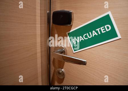 Schiffskabine mit einem Schild Evacuated Tuer einer Schiffskabine mit einem gruenen Schild und weissen Buchstaben auf dem das Wort Evacuated steht. Dieses Symbolbild signalisiert, dass die Kabine im Inneren verlassen wurde und betont die Bedeutung von Sicherheitsmaßnahmen an Bord des Schiffes Barcelona Spanien *** Ship cabin with a sign Evacuated Door of a ship cabin with a green sign and white letters on which is written the word Evacuated This symbol image signals that the cabin inside has been abandoned and emphasizes the importance of security measures on board the ship Barcelona Spain Stock Photo