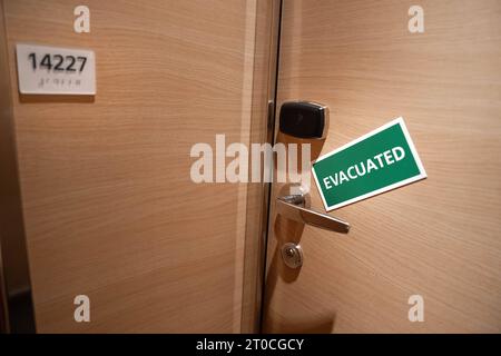 Schiffskabine mit einem Schild Evacuated Tuer einer Schiffskabine mit einem gruenen Schild und weissen Buchstaben auf dem das Wort Evacuated steht. Dieses Symbolbild signalisiert, dass die Kabine im Inneren verlassen wurde und betont die Bedeutung von Sicherheitsmaßnahmen an Bord des Schiffes Barcelona Spanien *** Ship cabin with a sign Evacuated Door of a ship cabin with a green sign and white letters on which is written the word Evacuated This symbol image signals that the cabin inside has been abandoned and emphasizes the importance of security measures on board the ship Barcelona Spain Stock Photo