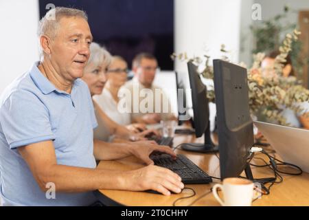 Old man learning computer programs in training room Stock Photo
