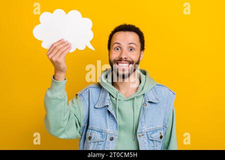 Photo portrait of nice young man excited hold speech bubble idea think wear trendy khaki clothes isolated on yellow color background Stock Photo
