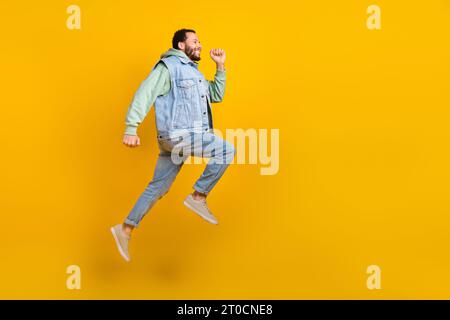 Full length size photo body cadre of running shopaholic guy spring time sale season promo denim apparel isolated on yellow color background Stock Photo
