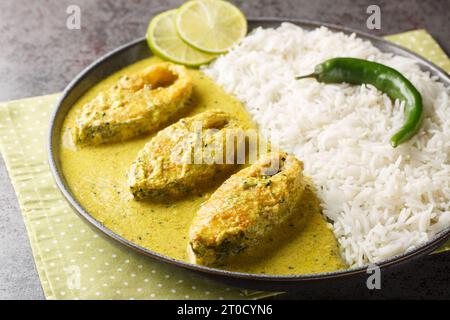 Bengali Shorshe Ilish or Hilsa cooked in Mustard Gravy served with white rice closeup on the plate on the table. Horizontal Stock Photo